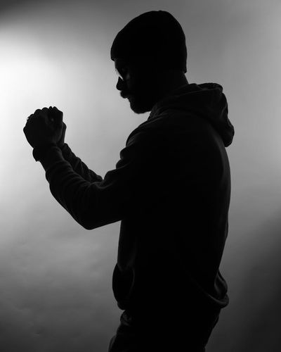 Silhouette of a man in a meditative pose against a dark background, embodying stillness.